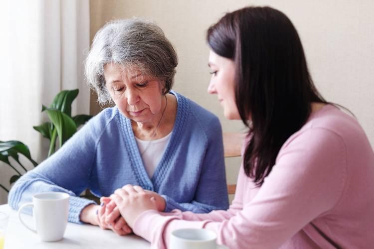 Image: younger woman holding the hands of an older woman